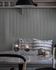 Dining area with marble table, black pendant light, and striped cushions on a gray wall.