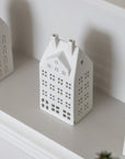 White ceramic house-shaped lantern on a white surface