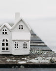 Two small white houses on a wooden pier with water in the background