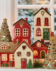 Decorative ceramic houses and trees on a windowsill with a snowy outdoor background.