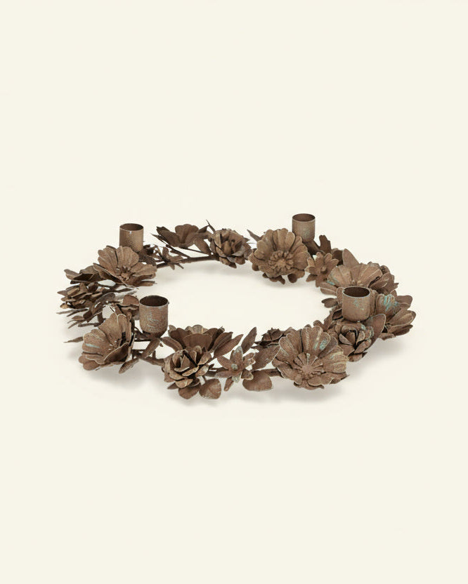 Decorative wreath with floral designs and candle holders on a white background