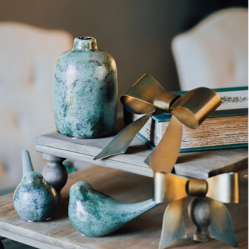 Decorative items including a vase, birds, and a bowl on a wooden surface with a blurred background.