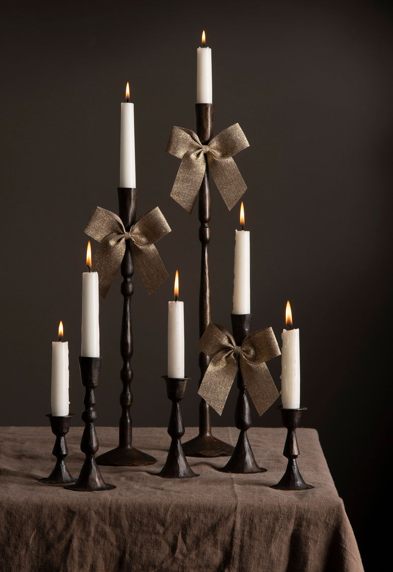 Decorative candlesticks with lit candles and ribbons on a dark background