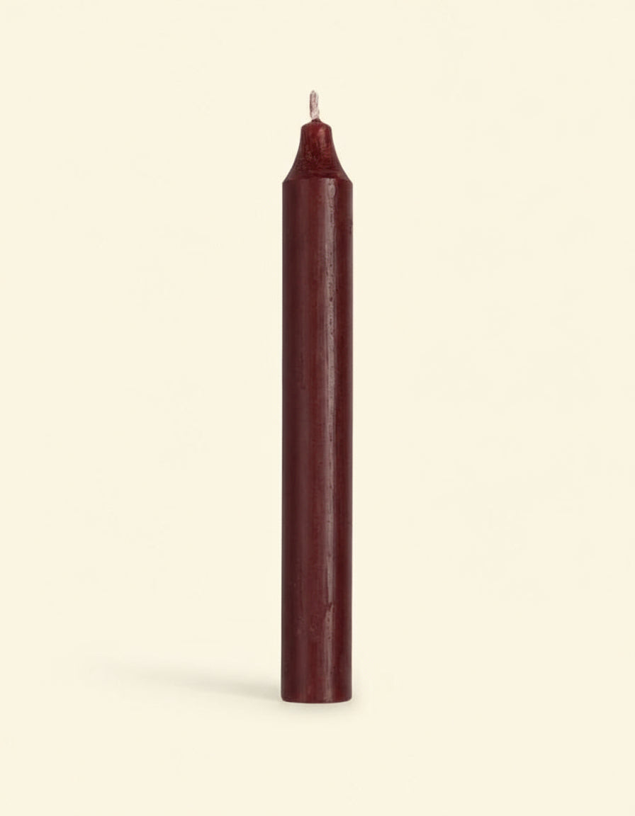 Single burgundy candle on a white background