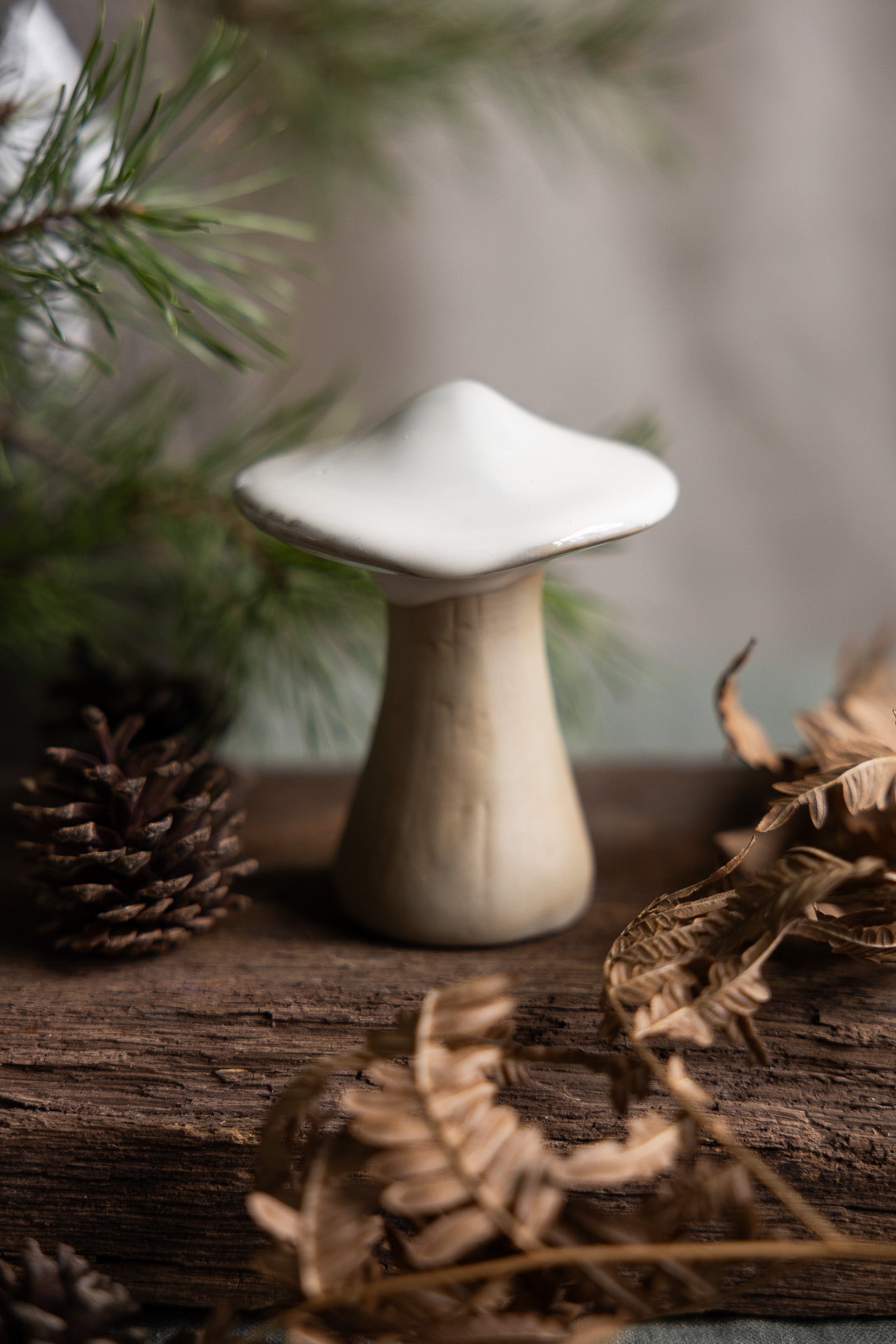 Mushroom-shaped decorative object on a wooden surface with foliage in the background