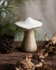 Mushroom-shaped decorative object on a wooden surface with foliage in the background