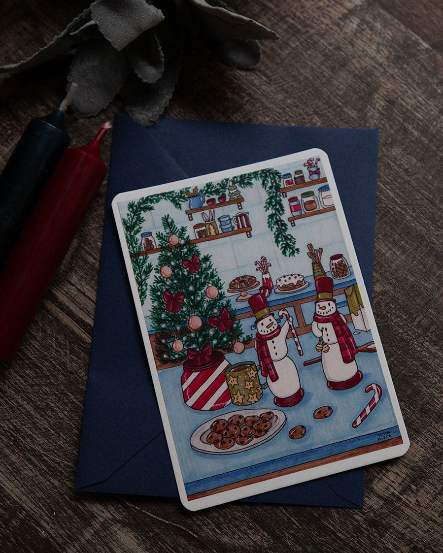Decorative Christmas card with a snowy village scene on a wooden surface.