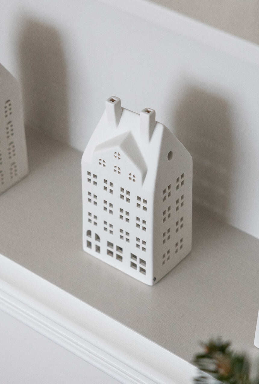 White ceramic house-shaped lantern on a white surface