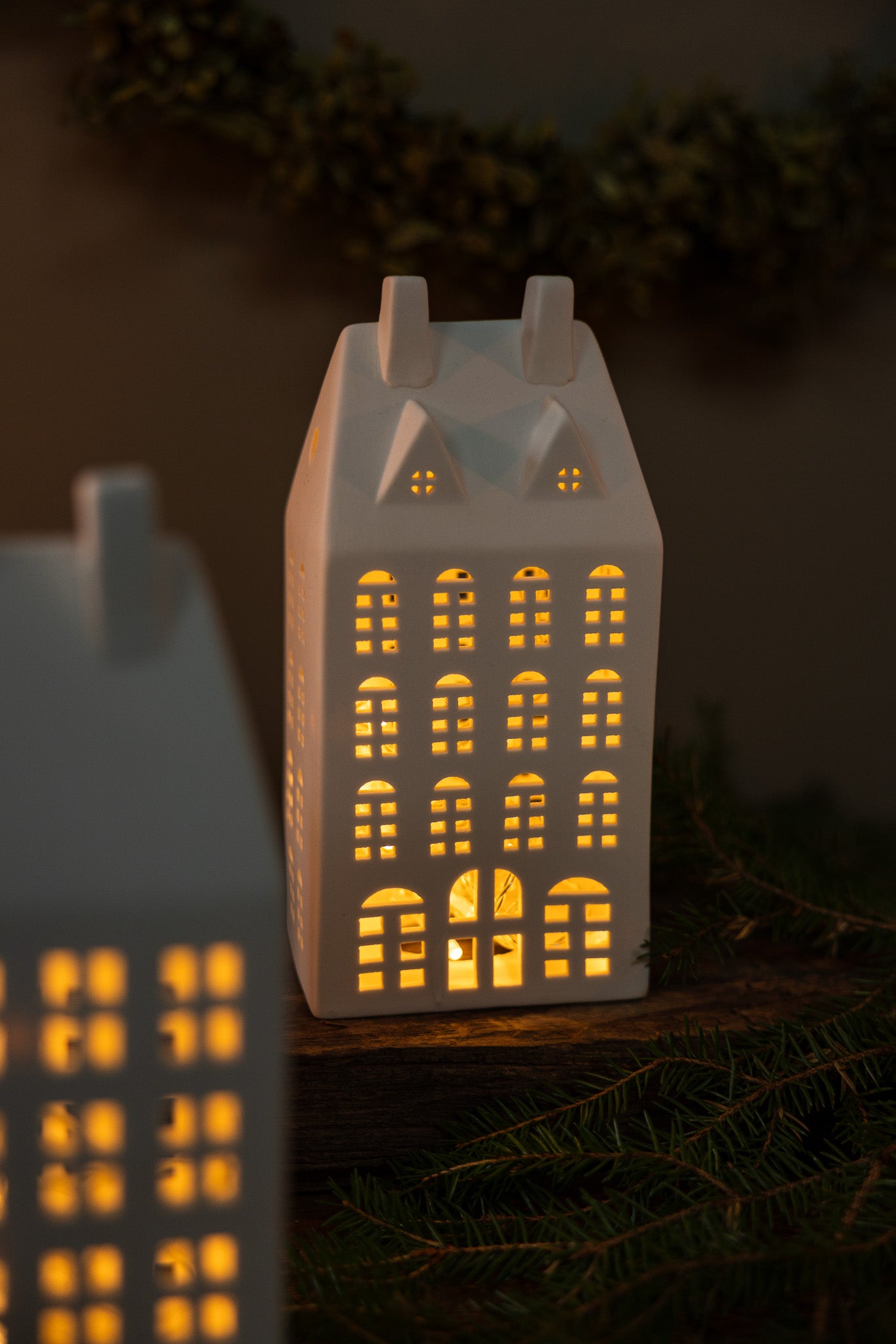 Ceramic house-shaped lamp with glowing windows on a dark background