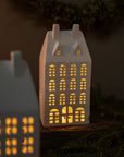Ceramic house-shaped lamp with glowing windows on a dark background