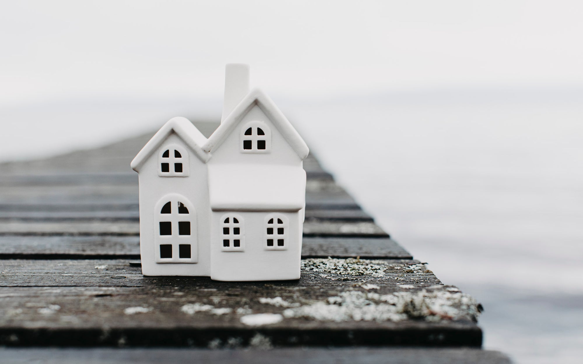 Two small white houses on a wooden pier with water in the background