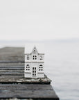 Small model house on a wooden pier extending into a body of water.