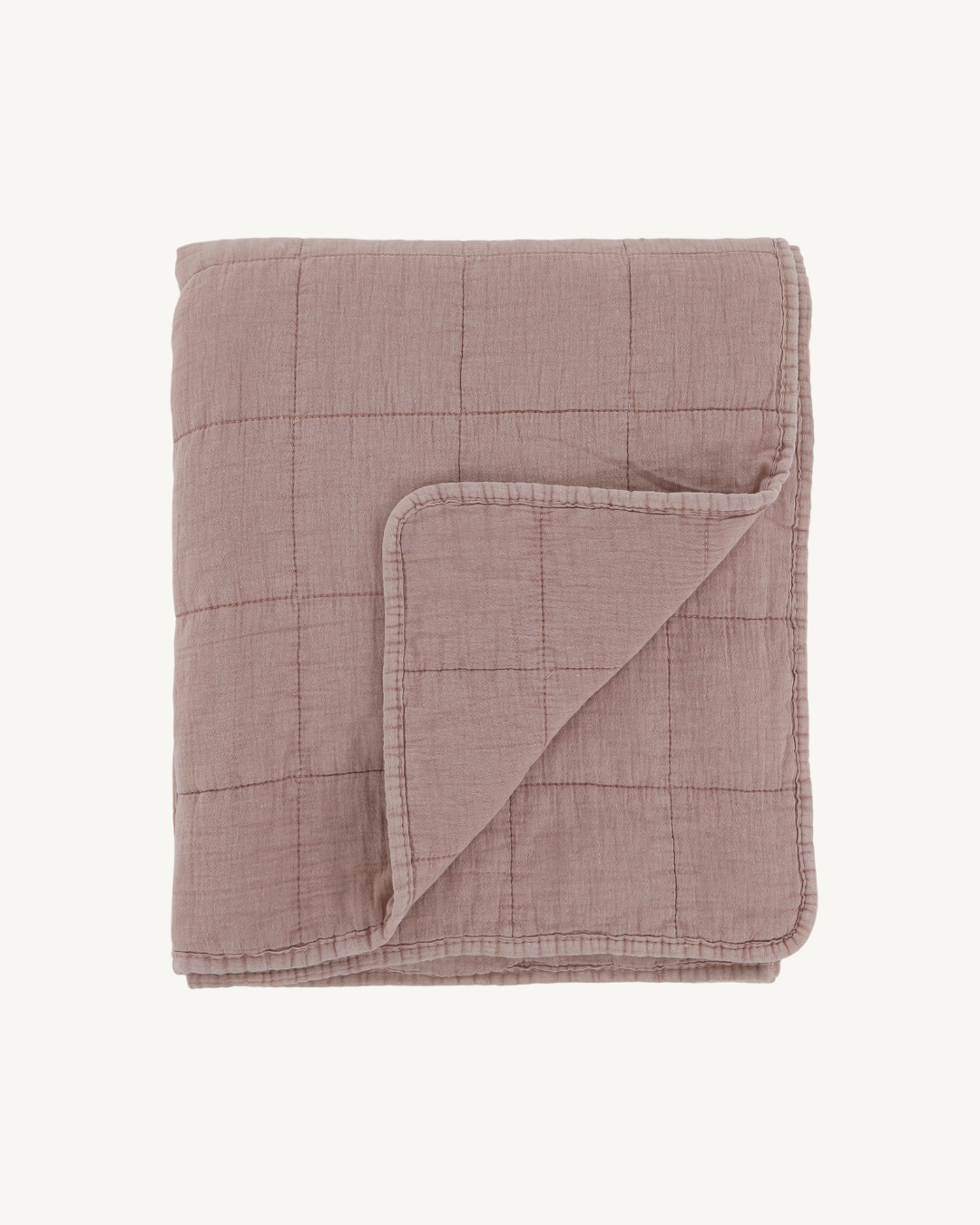 Folded pink quilt on a white background