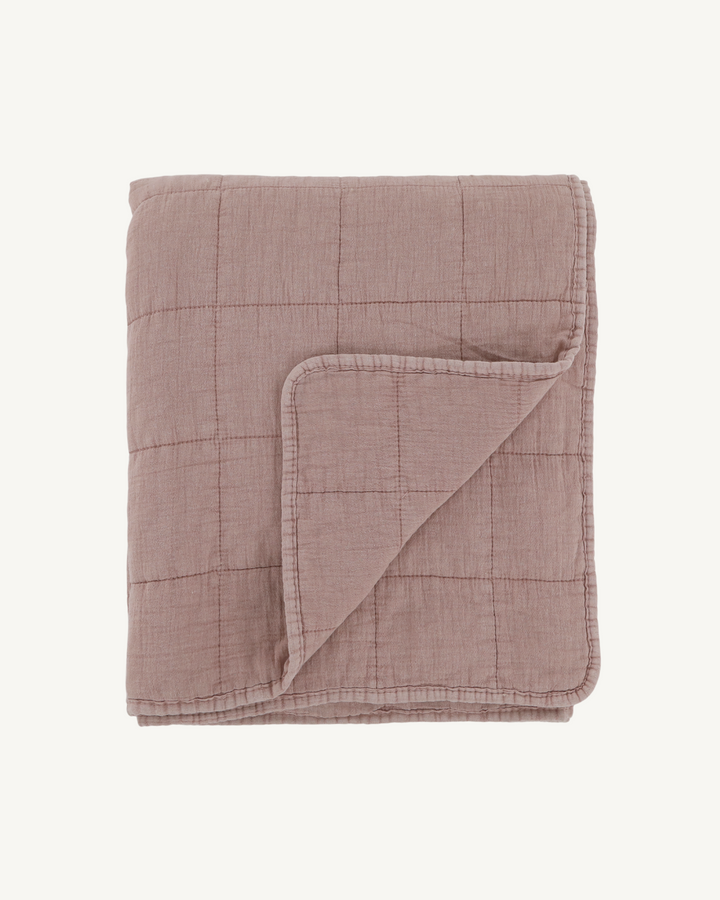 Folded pink quilt on a white background